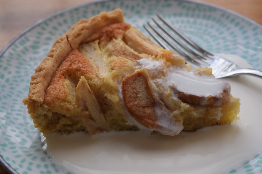 Slice of pear frangipane tart on a plate with cream